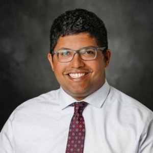 A smiling man wearing glasses and a tie