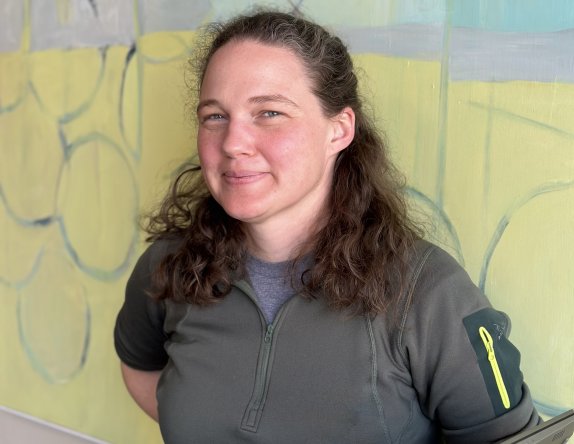 a woman with brown hair wearing a gray shirt