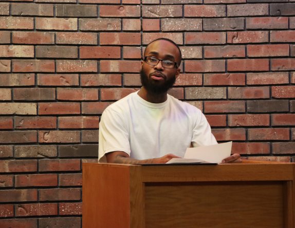 man with glasses speaking behind a podium