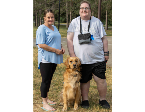 a woman standing next to a young man with a dog sitting between them