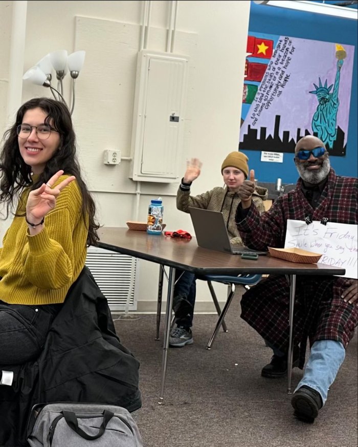 Three seated adults in a classroom looking at the camera