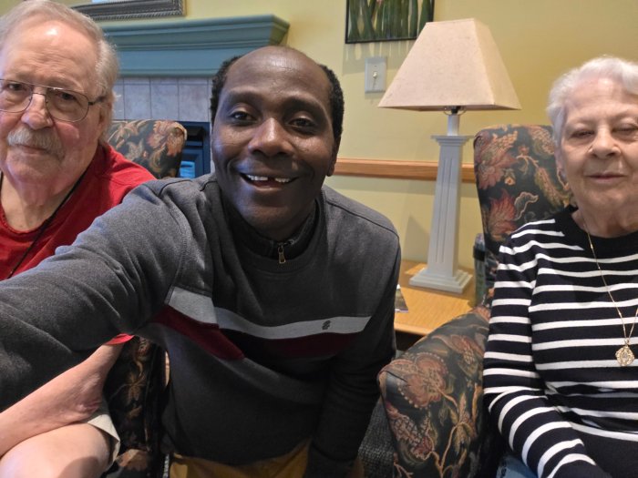 a man talking a selfie with two older adults sitting on each side