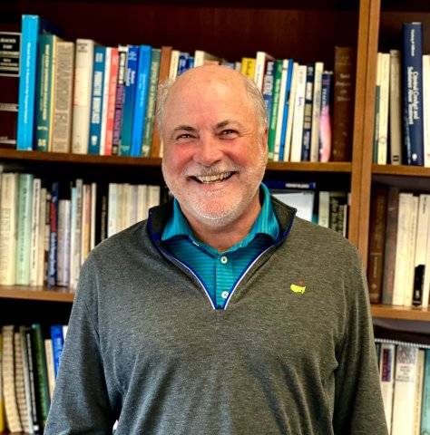 a smiling older man in front of a bookcase