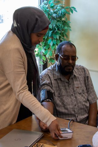 A Community Health Worker checking the blood pressure of her client