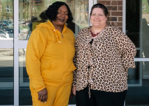 Two women standing outside a building smiling