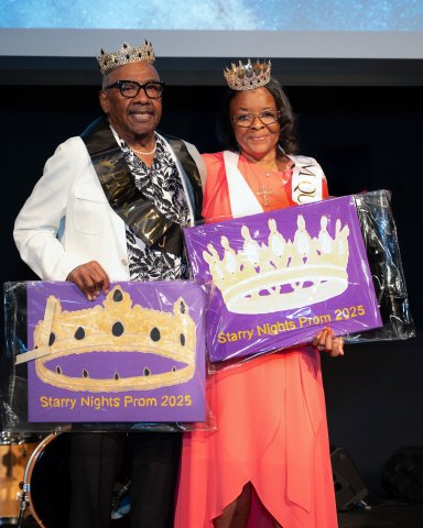 A man and woman wearing crowns smiling