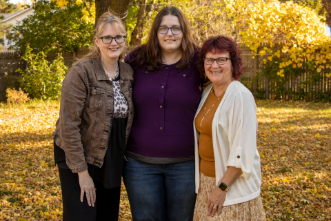 Three woman standing together outside in the fall. 