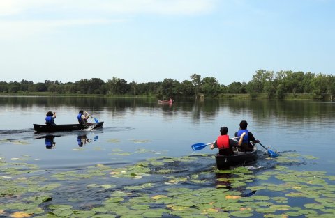 two pairs of students in two canoes on a lake