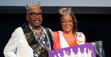 A man and woman wearing crowns smiling
