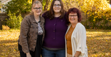 Three woman standing together outside in the fall. 