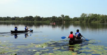 two pairs of students in two canoes on a lake