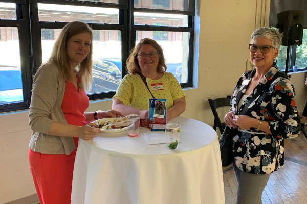 3 VOA staff members standing at a table enjoying a meal