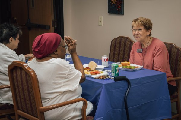 three women sitting at a table talking and eating