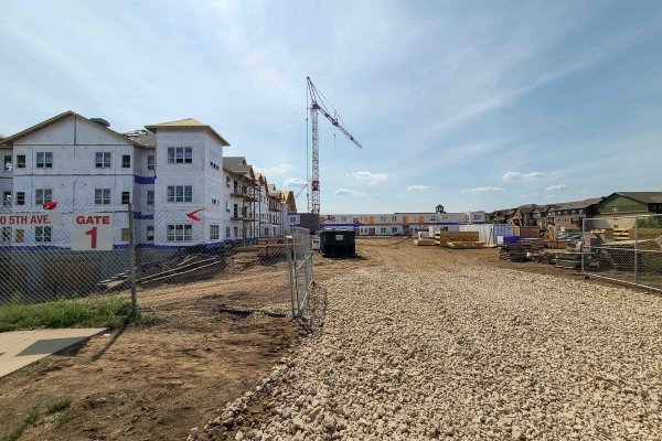 Construction site of an apartment building being built inside a fenced in area