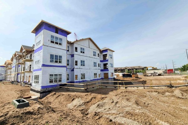 Construction site of an apartment building being built with apartment building in the back