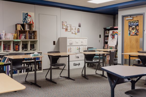 Classroom one with desks in a circle, a bookshelf in the back and student art on the walls this is where school takes place everyday