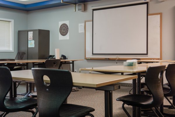 Classroom two with desks and a projector screen on the wall