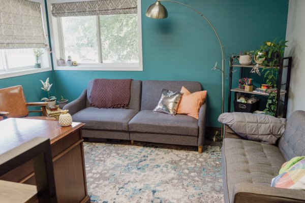 A therapist's office with two couches, a desk and a bookshelf in the corner