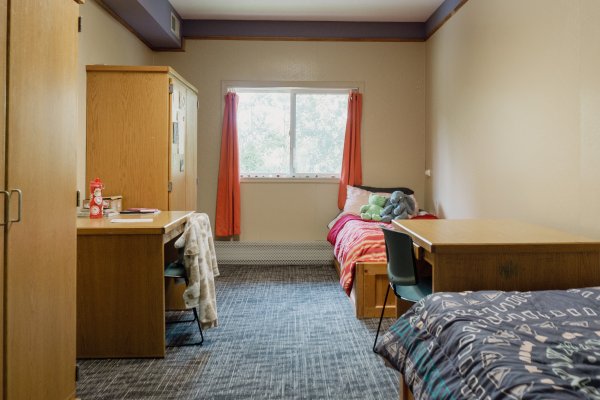 Resident bedroom with two beds on right side separated by a desk and two wardrobes on left side separated by a desk