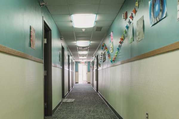 Hallway in the dorm building, bedroom and bathroom doors line the hallway and the walls are decorated with resident artwork