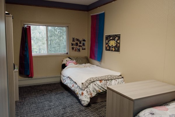 Resident bedroom with bed in corner and a small dresser on right side