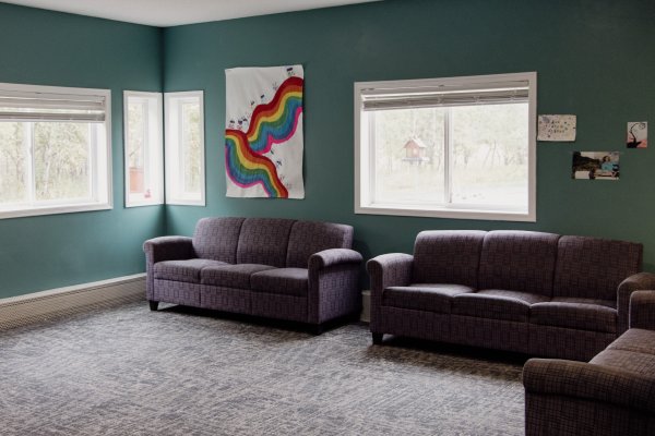 Large lounge room with couches on far wall and student artwork on wall behind couches