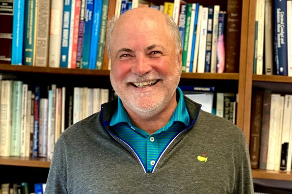 A man smiling in front of a bookcase