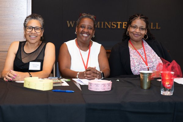 A group of women sitting behind a table smiling