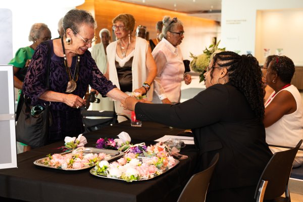 An older woman checking into to the senior prom and receiving a corsage