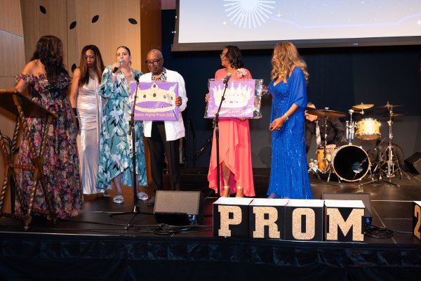 A group of people standing on stage preparing to crown the king and queen of senior prom