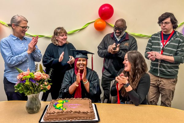 A group of people gathered around a decorated cake, surrounded by colorful balloons, celebrating a special occasion.