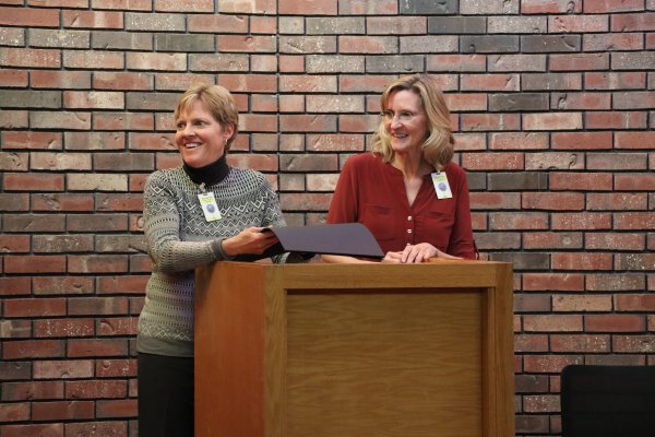 two women smiling and standing behind a podium