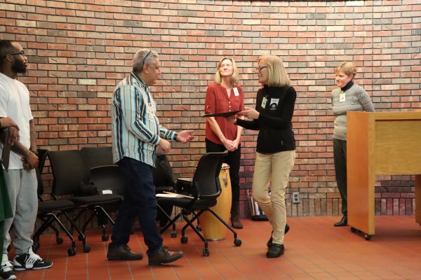 a woman handing a man a certificate for completion of the CPE program