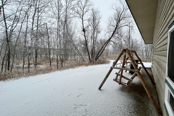 Outdoor wood patio swing next to the Avanti building covered in snow