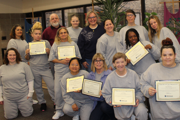 a group of people standing and kneeling together, most are women in grey outfits
