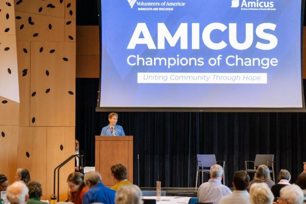 A woman standing at a podium in front of a large audience seated at tables