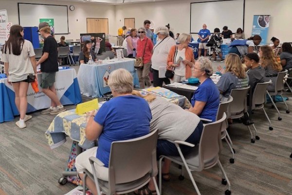 people sitting at tables in a large room connecting volunteers to opportunities