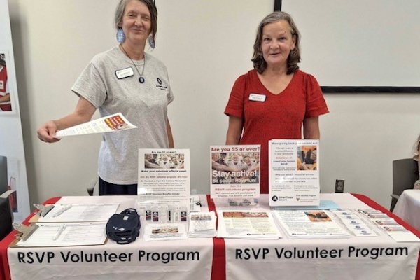 two women standing behind a table handing out informational flyers